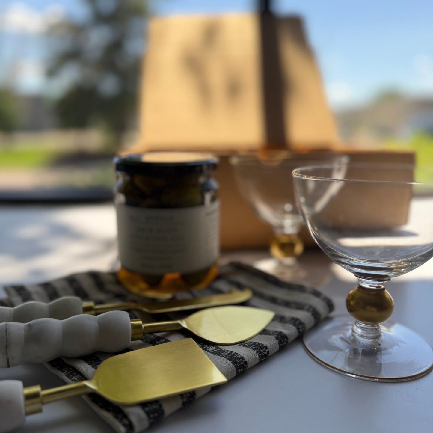 Table setting with gold cutlery, glass, and jar on a white surface with blurred background