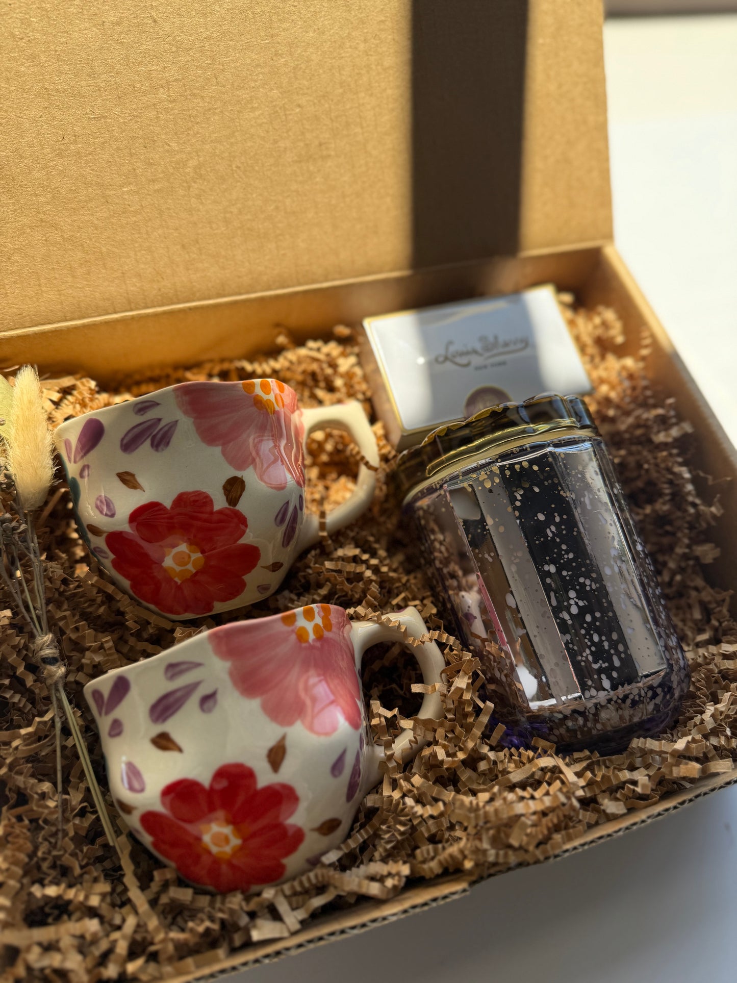 Two floral ceramic cups and a small glass jar with a lid in a gift box.