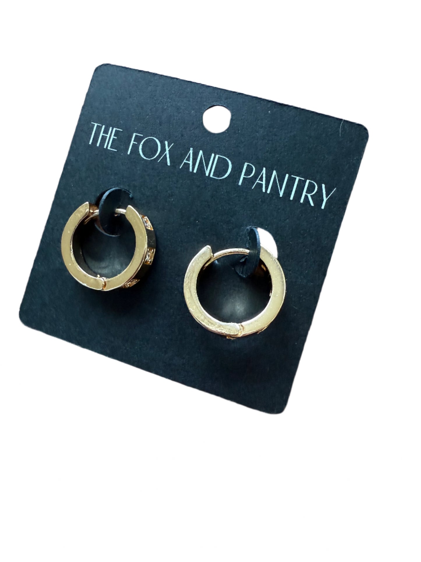 Pair of gold hoop earrings on a black card with 'The Fox and Pantry' branding, placed on a wooden surface.