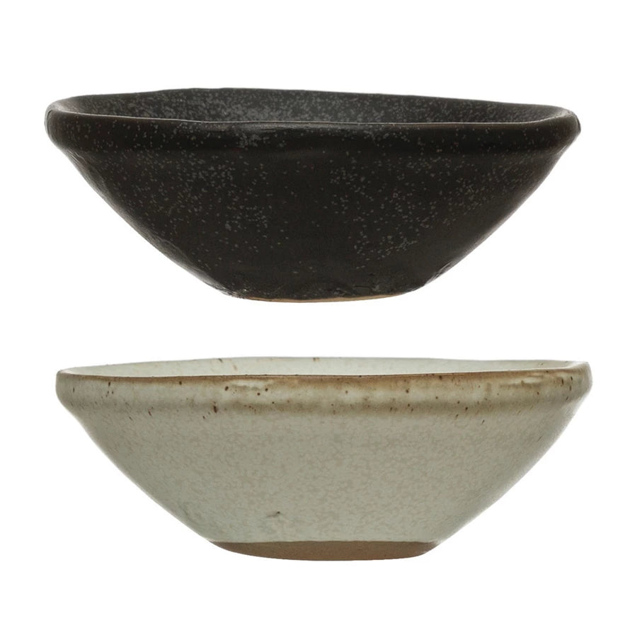 Two ceramic bowls, one black and one beige, on a white background