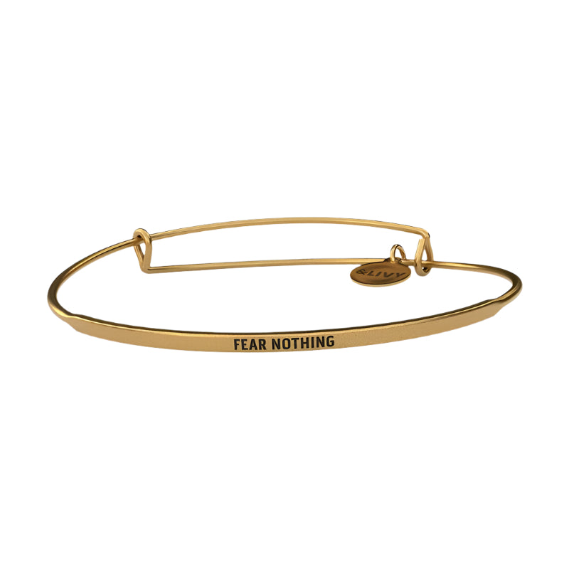 Gold bracelet with 'FEAR NOTHING' engraving on a white background