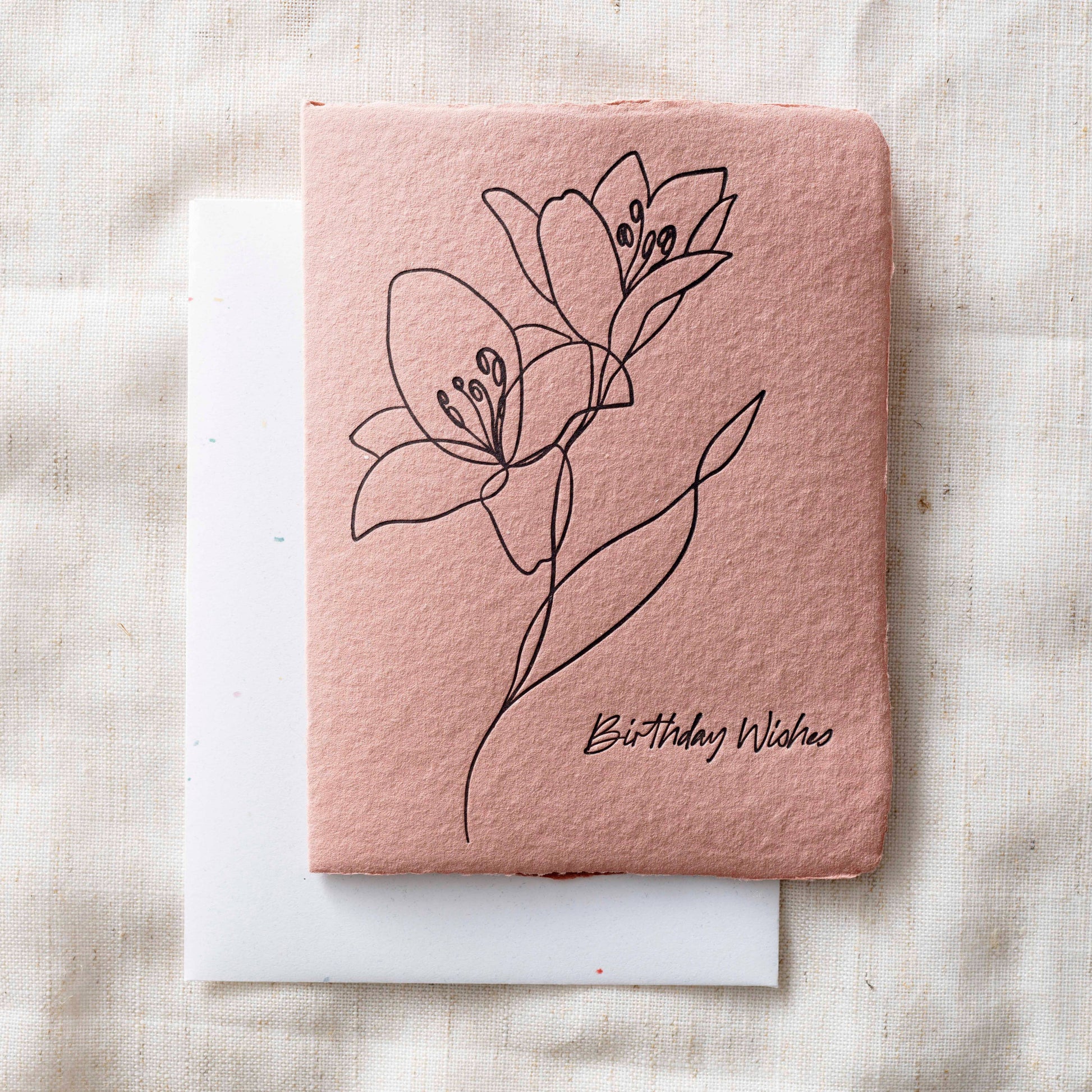 Pink card with floral design and 'Birthday Wishes' text on a textured surface