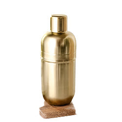 Brass cocktail shaker on a wooden coaster with a white napkin in the background