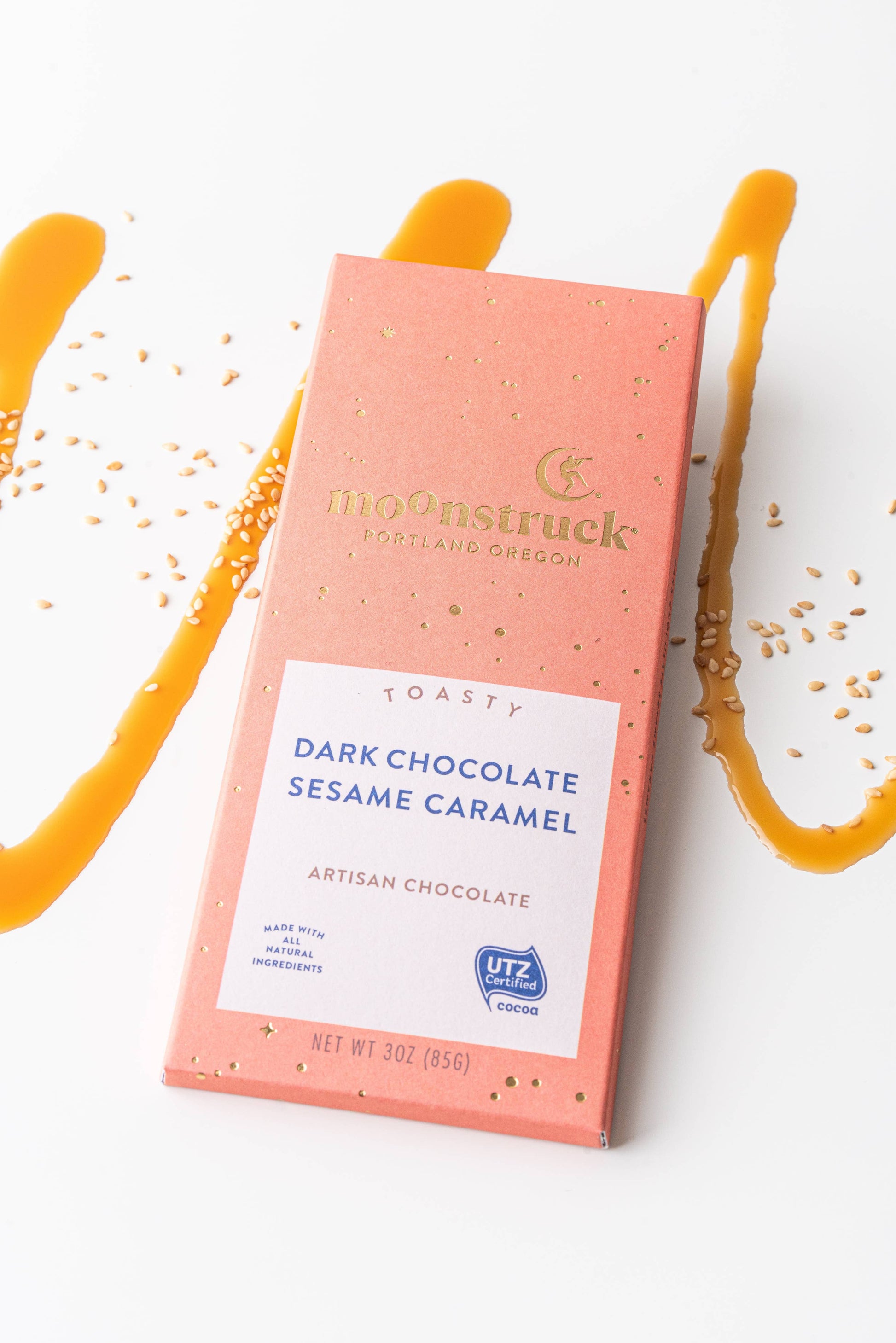 Moonstruck dark chocolate sesame caramel bar packaging on a white background with caramel drizzle.