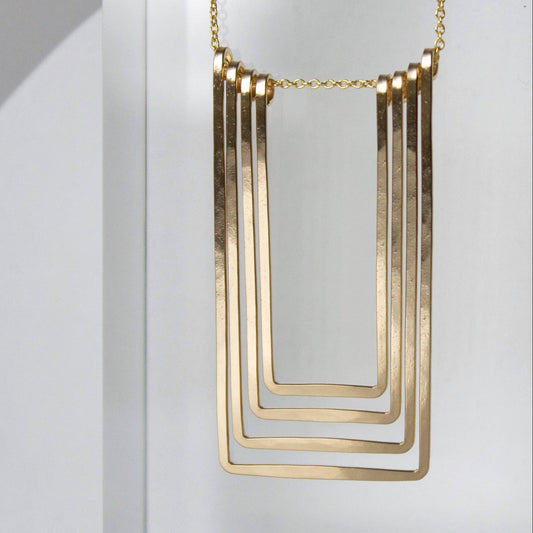 Gold necklace with geometric design on a white background