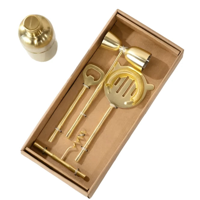 Set of gold cocktail tools in a box on a marble surface