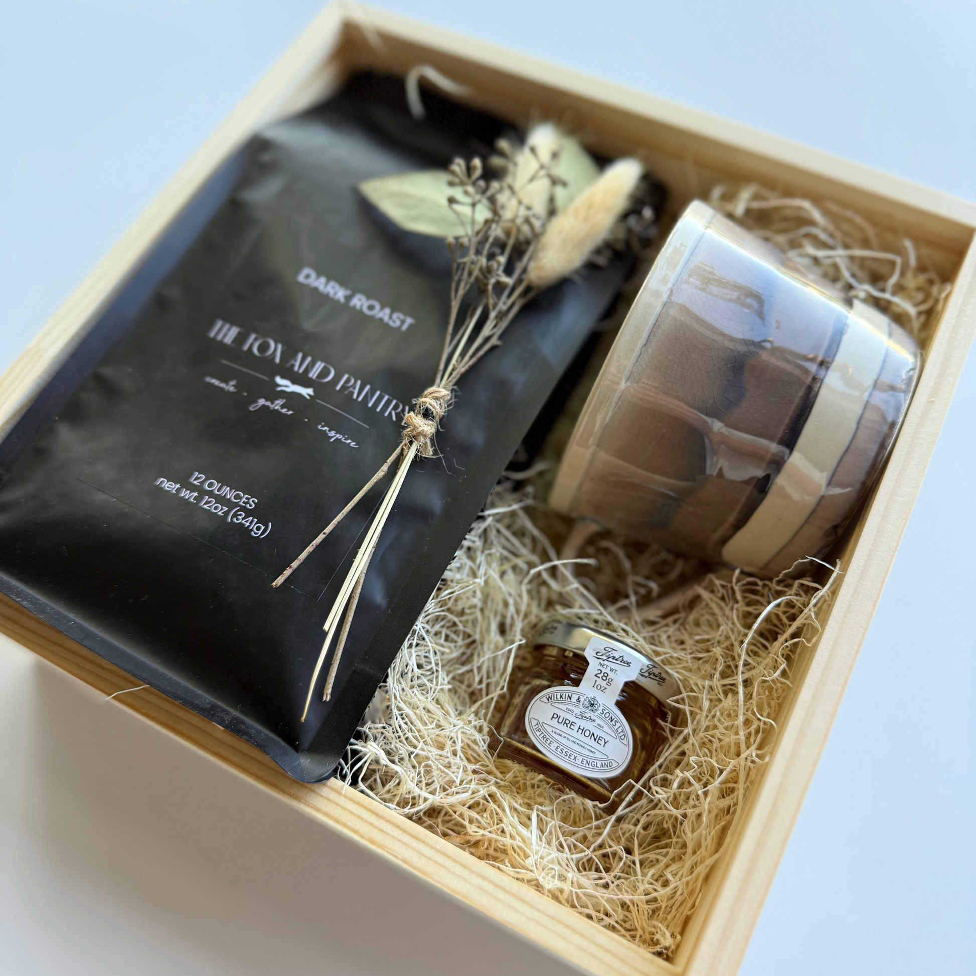 Gift set with coffee package, jar, and decorative elements in a wooden box.