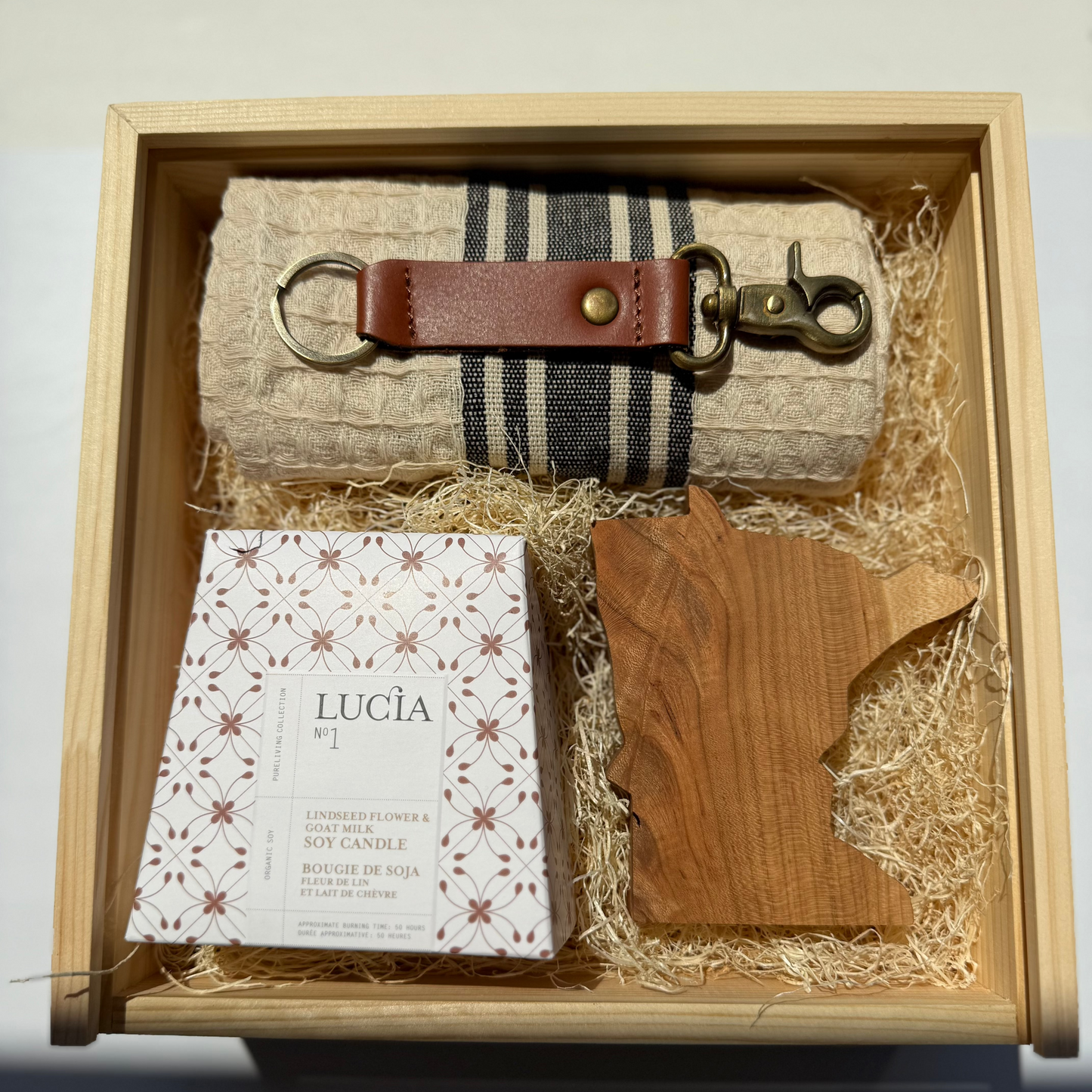 Gift set with keychain, wooden state-shaped item, and candle in a wooden box.