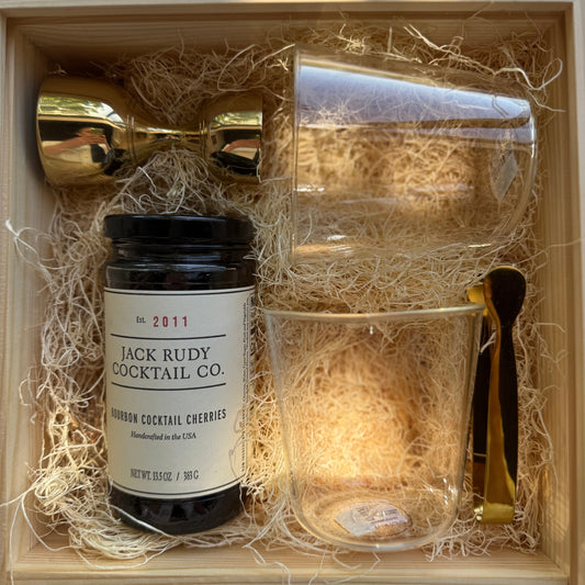 Gift set with Jack Rudy cocktail cherries, glasses, and a spoon in a wooden box.