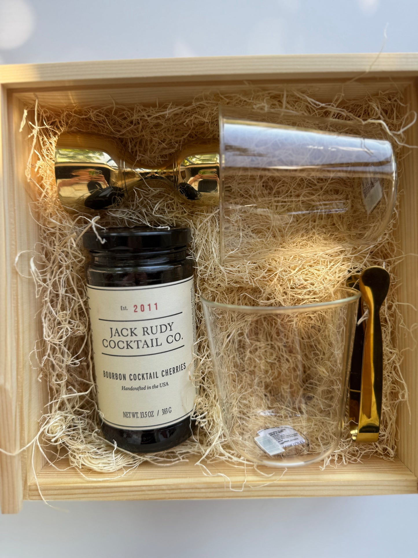 Cocktail kit with bottle, glass, and tools in a wooden box