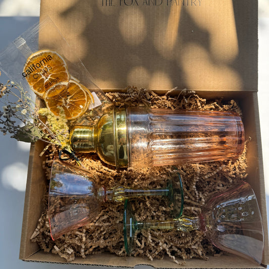 Gift set with glasses, bottle, and decorative elements in a box labeled 'The Fox and Pantry'.