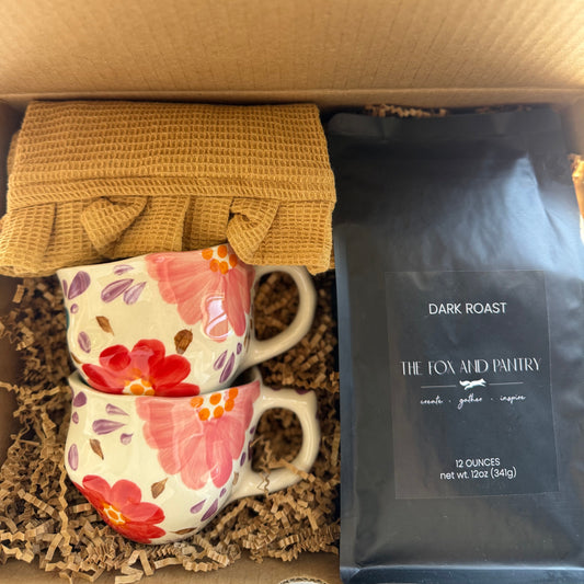 Two floral mugs and a dark roast coffee package in a box from The Fox and Pantry.