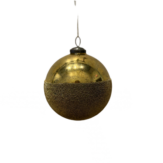 Gold Christmas ornament hanging against a white wall