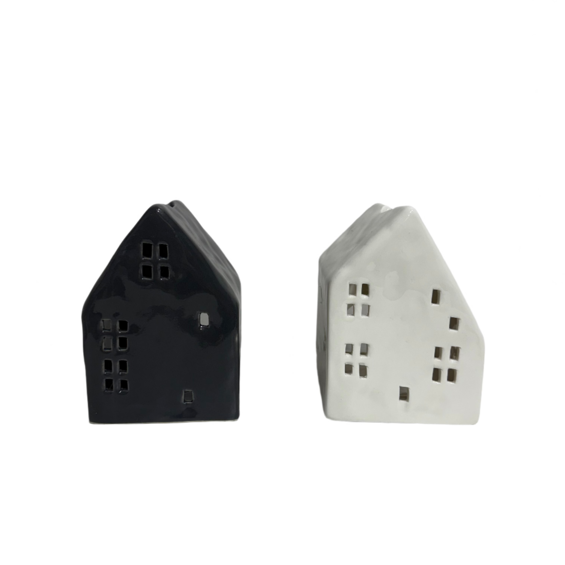 Two house-shaped ceramic lamps, one black and one white, on a white surface with a plain background.