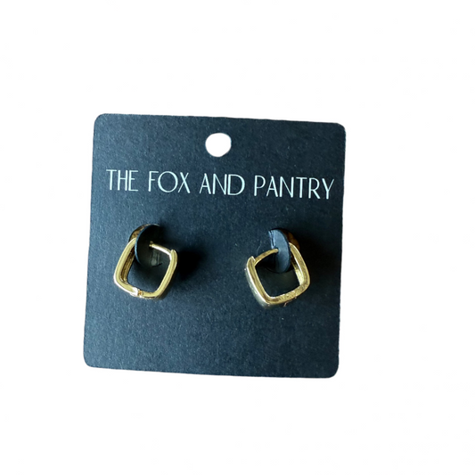 Pair of gold earrings on a 'The Fox and Pantry' branded card against a wooden background
