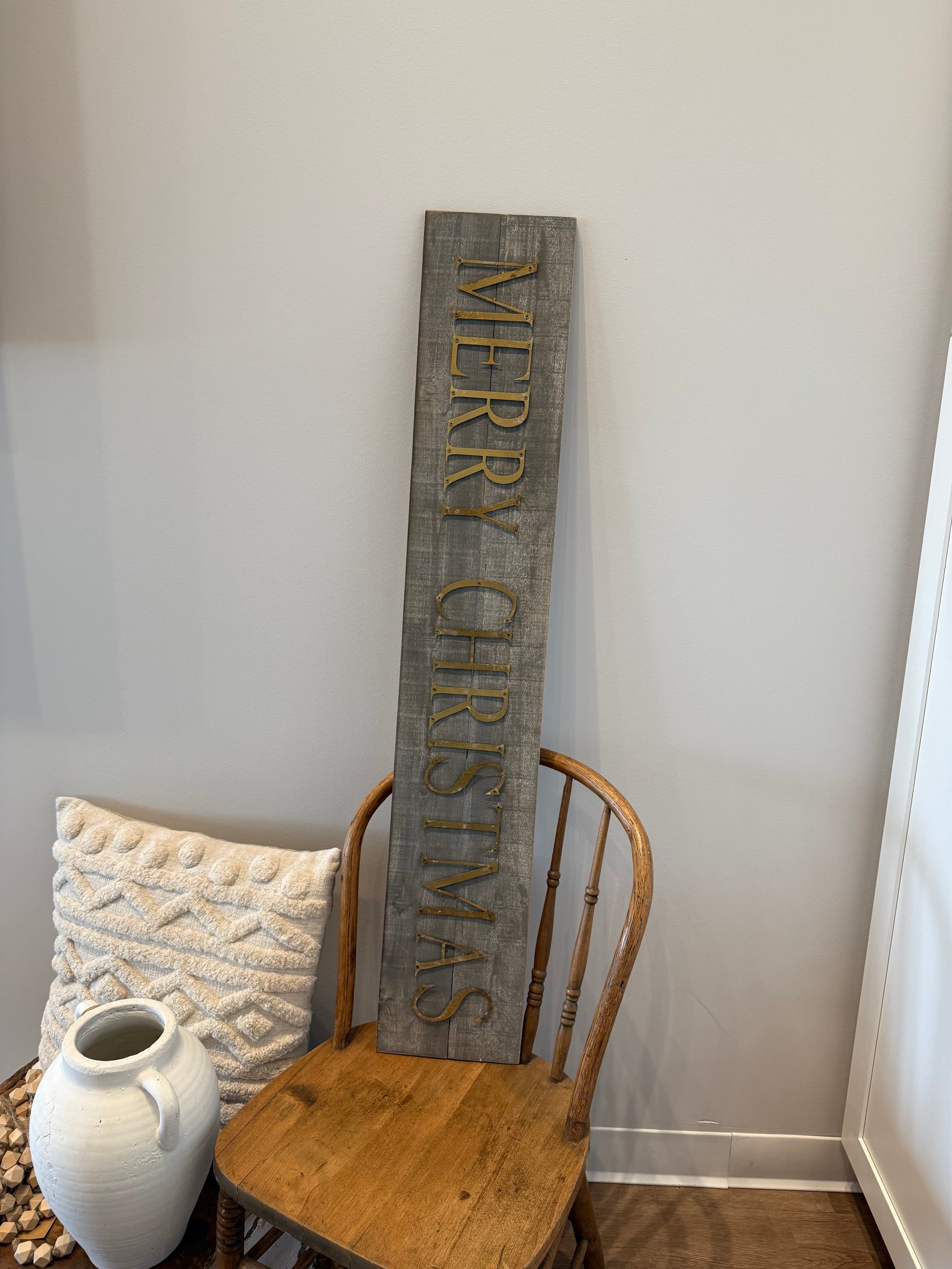 Wooden 'Merry Christmas' sign on a white wall with a rustic decor setting.
