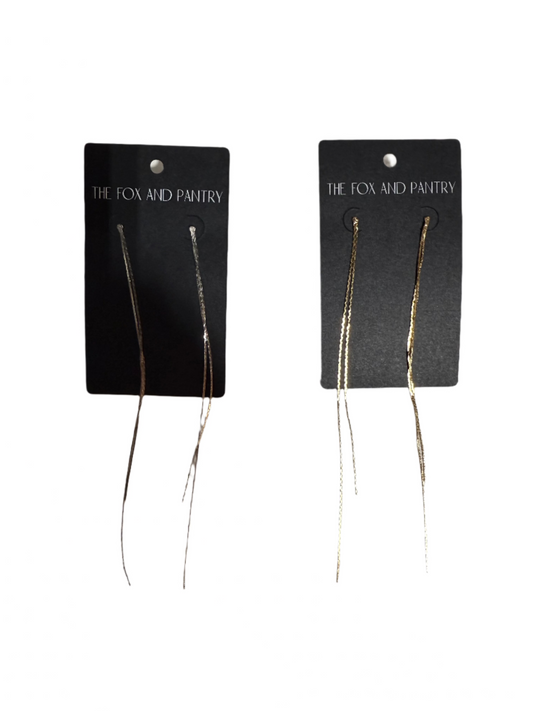 Pair of gold earrings on black cards with 'The Fox and Pantry' branding against a light background.