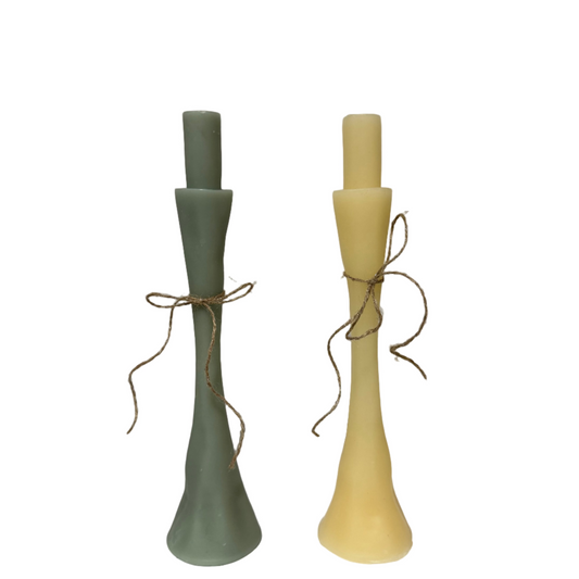 Two candlesticks, one green and one yellow, tied with twine on a white surface.