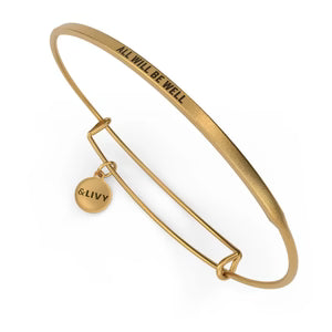 Gold bangle with 'All will be well' engraving and 'LOVE' tag on a white background