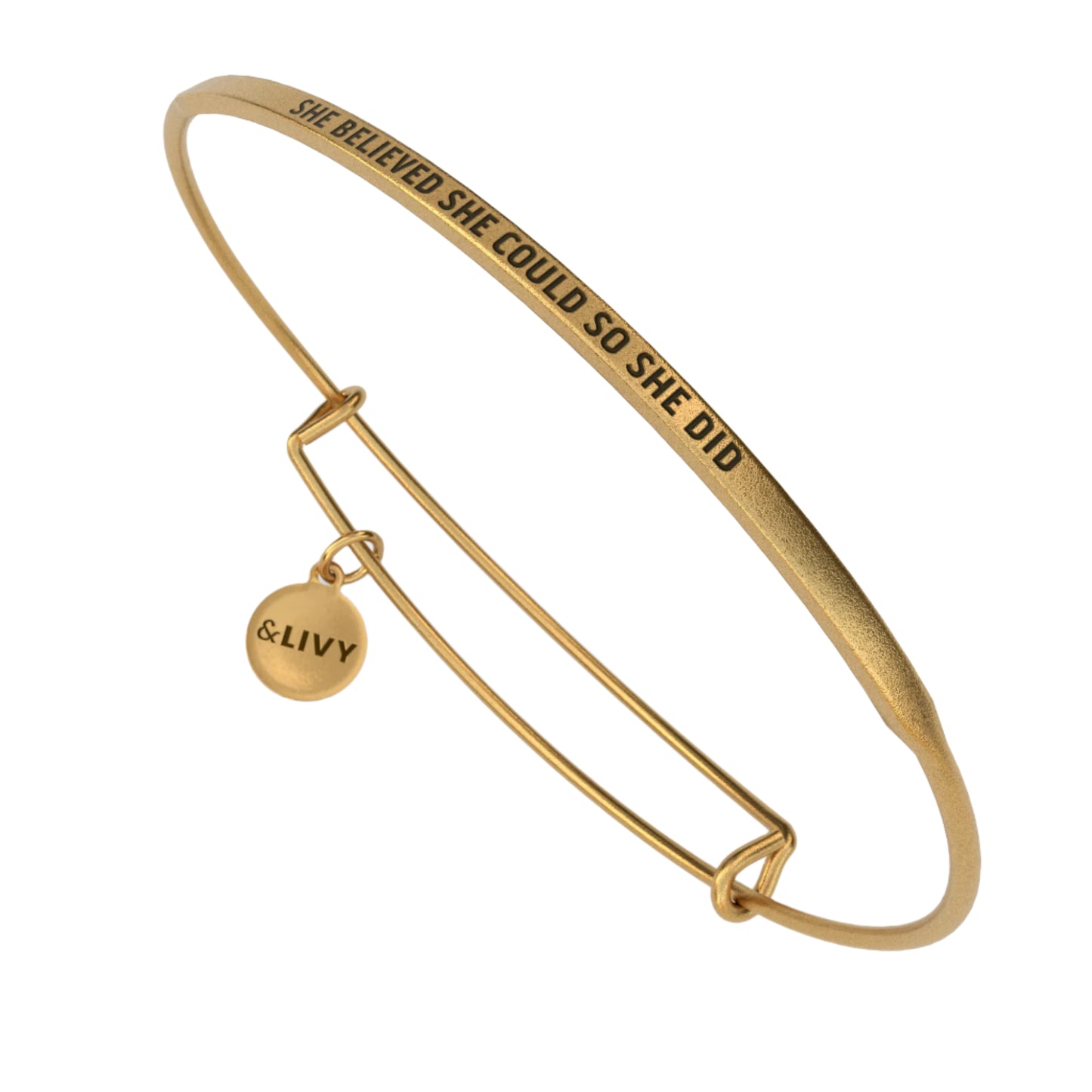 Gold bangle with engraved text and a small round tag on a white background