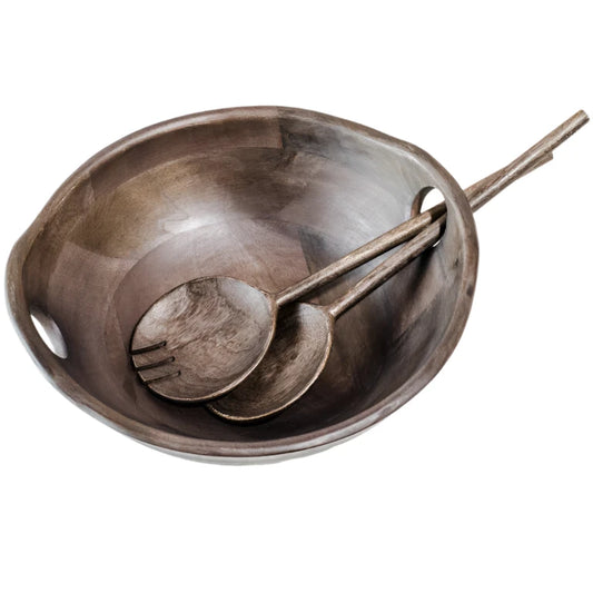 Wooden salad bowl with two spoons on a marble countertop