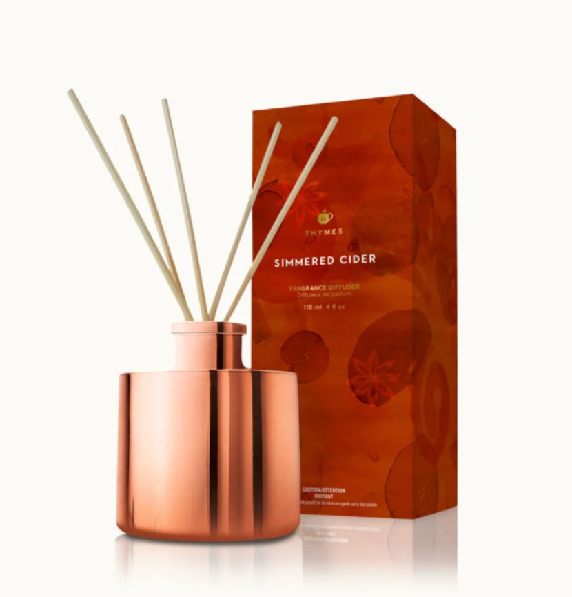 Copper diffuser with reeds and 'Thymes Simmered Cider' packaging on a white background
