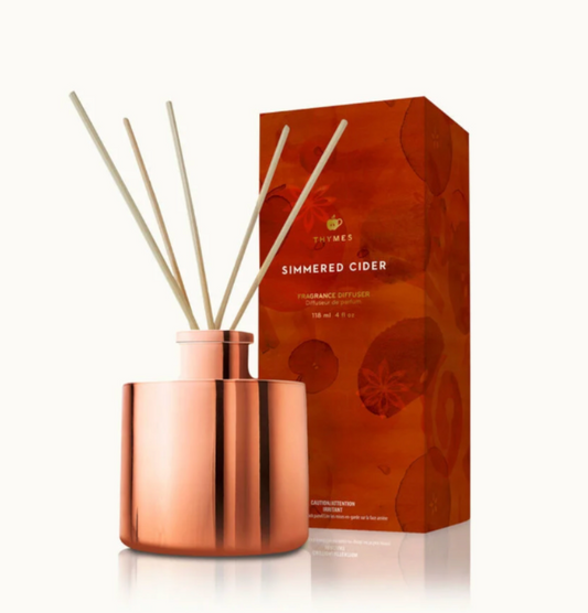 Copper diffuser with reeds and 'Thymes Simmered Cider' packaging on a white background