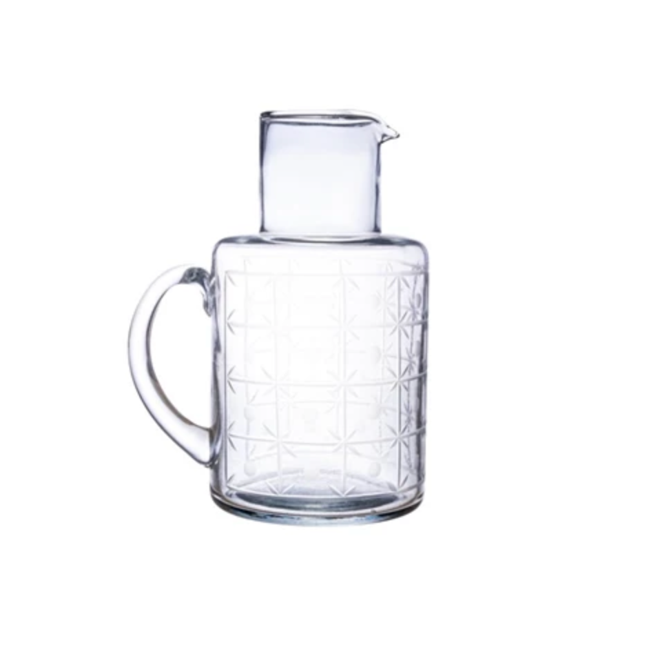Clear glass carafe with geometric pattern on a white background