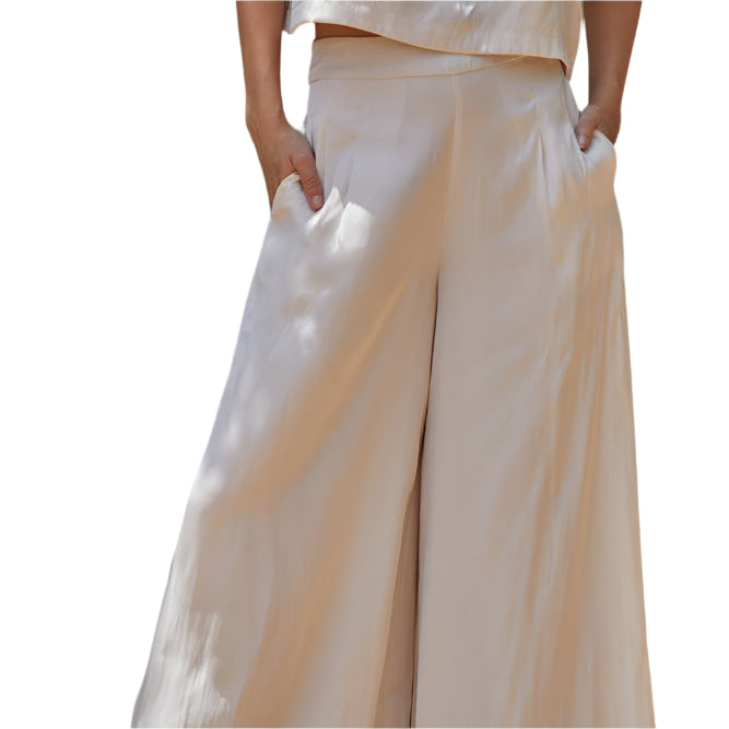 Person wearing a white outfit with wide-leg pants against a neutral background