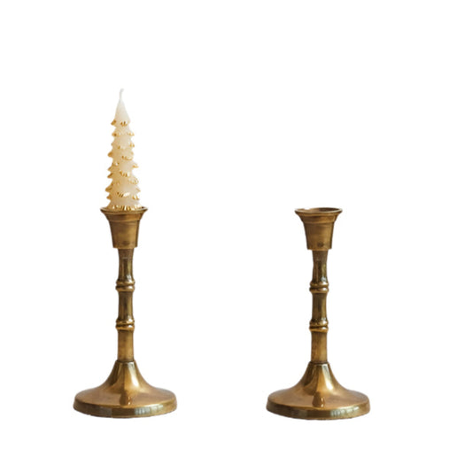 Two brass candlesticks on a textured white surface with a light gray background