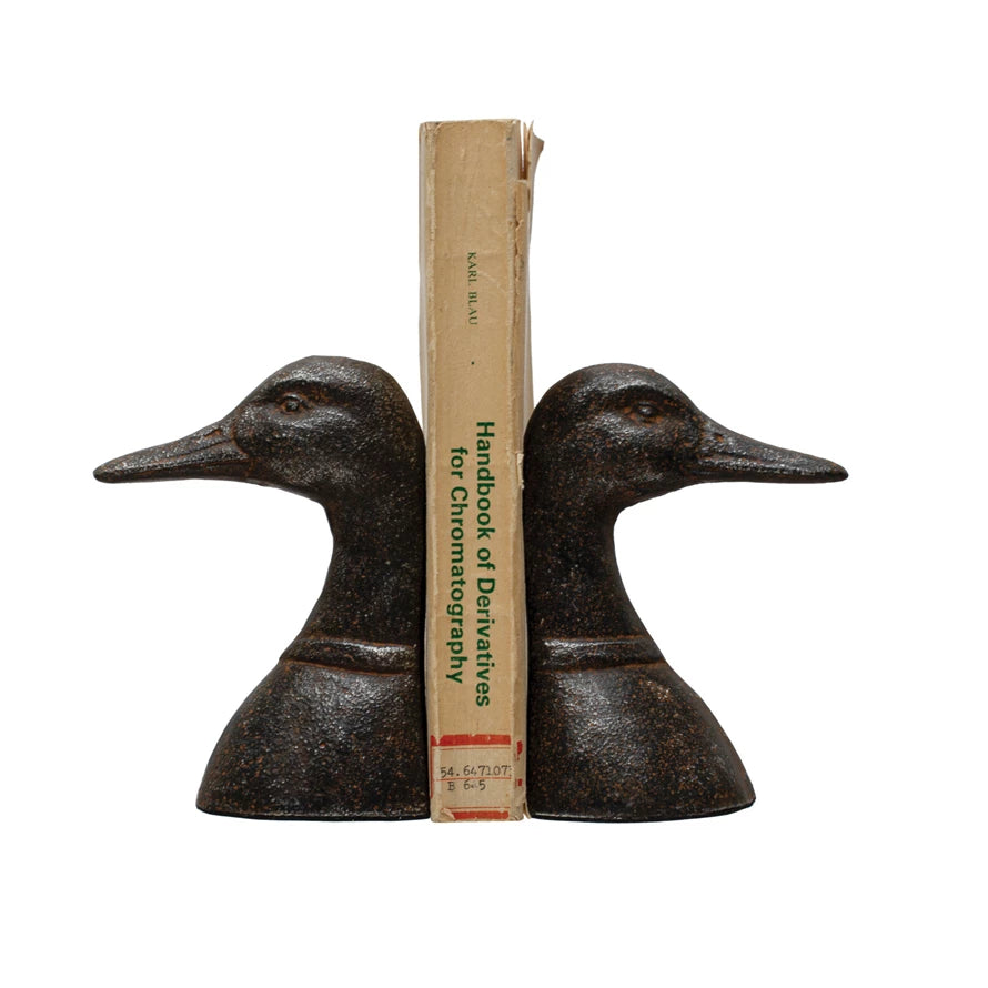 Pair of duck-shaped bookends holding a book on a white background