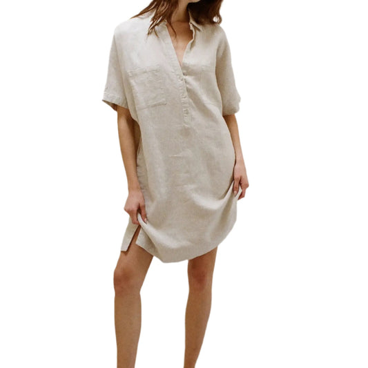 Woman wearing a light-colored linen dress in a minimal indoor setting