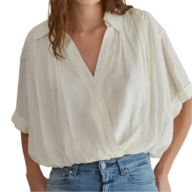 Woman wearing a white blouse and blue jeans against a plain background