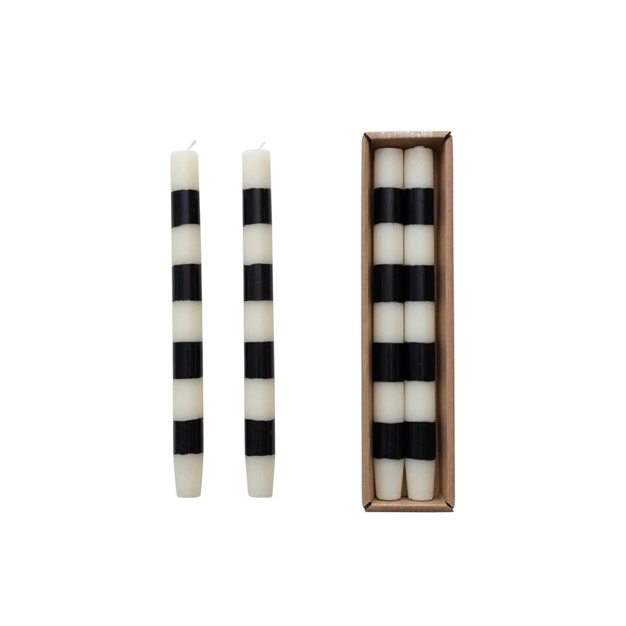 Black and white striped candles with one candle outside the box on a white background